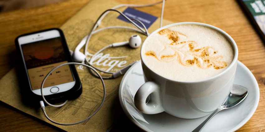 Telemóvel com auscultadores e chávena de café