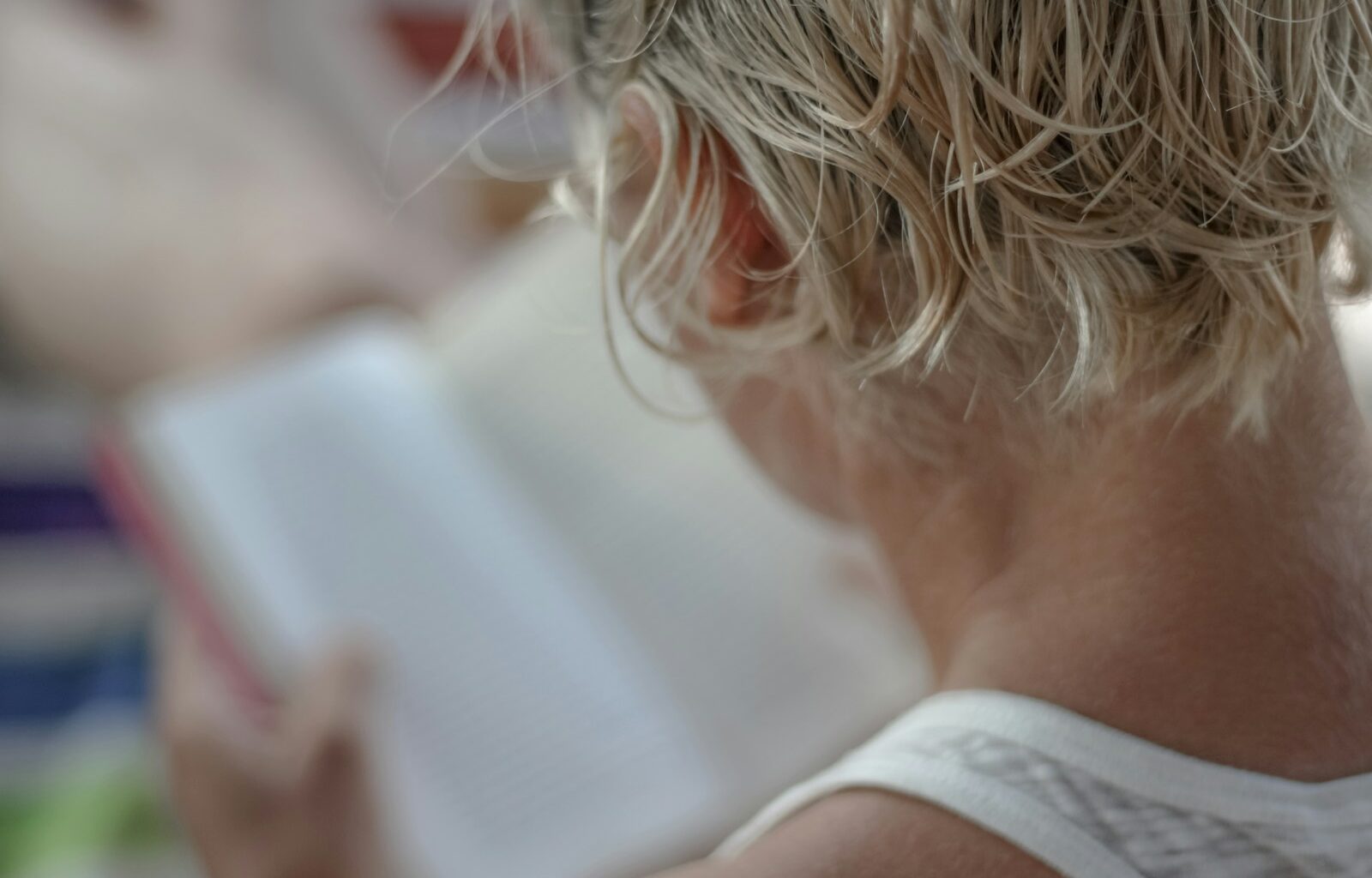 person in white tank top holding book