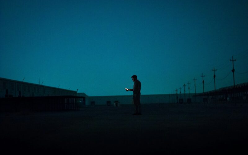 A lone figure uses a glowing device.