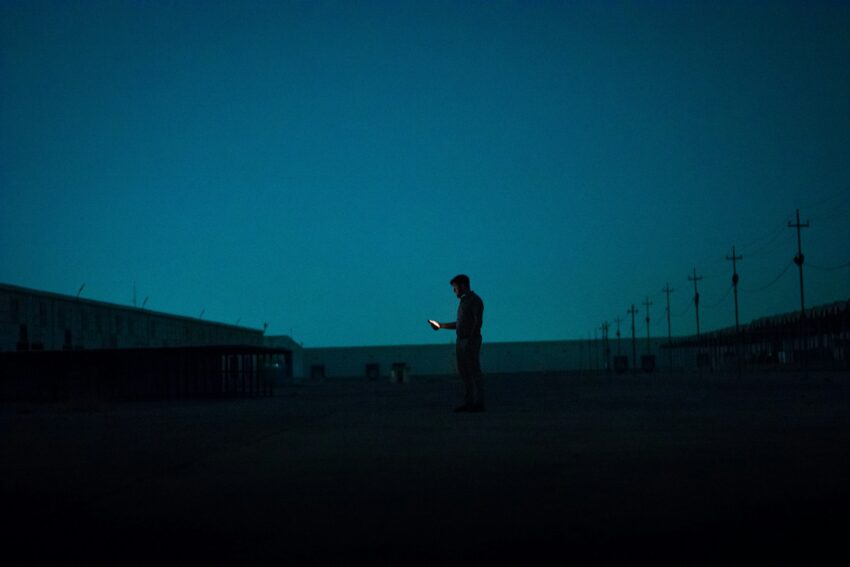 A lone figure uses a glowing device.