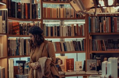 woman in brown coat reading book in library