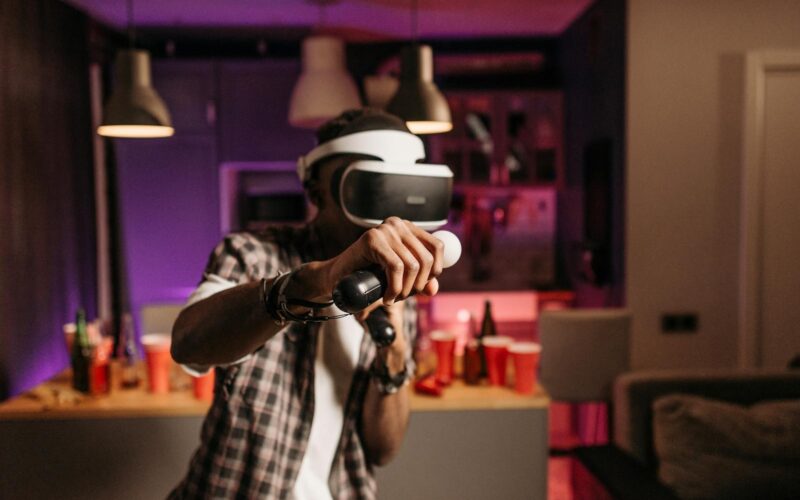 Young adult playing virtual reality games with headset and controller in a stylish indoor setting.