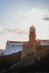 Lighthouse stands tall against a bright, cloudy sky.