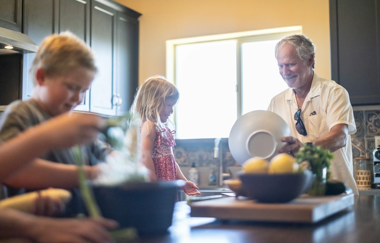 Grandfather and grandchildren prepare food in kitchen